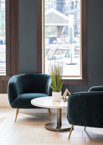 a seating area with two green chairs and a white coffee table with a plant  at The Clearing at ONE28, Olathe, KS